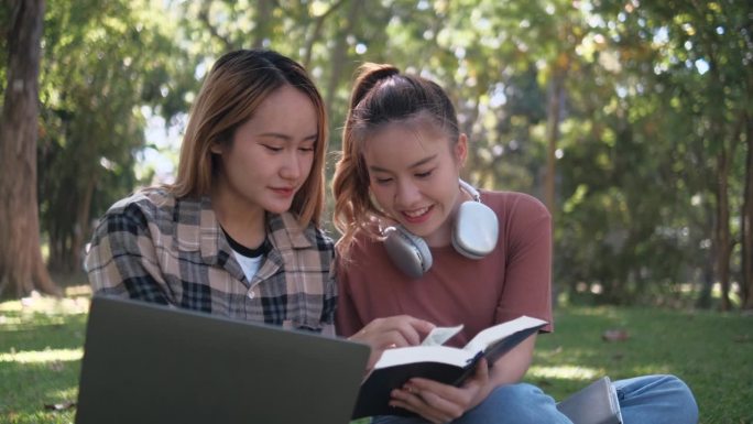 两名女学生坐在大学校园的草地上一起工作和学习考试