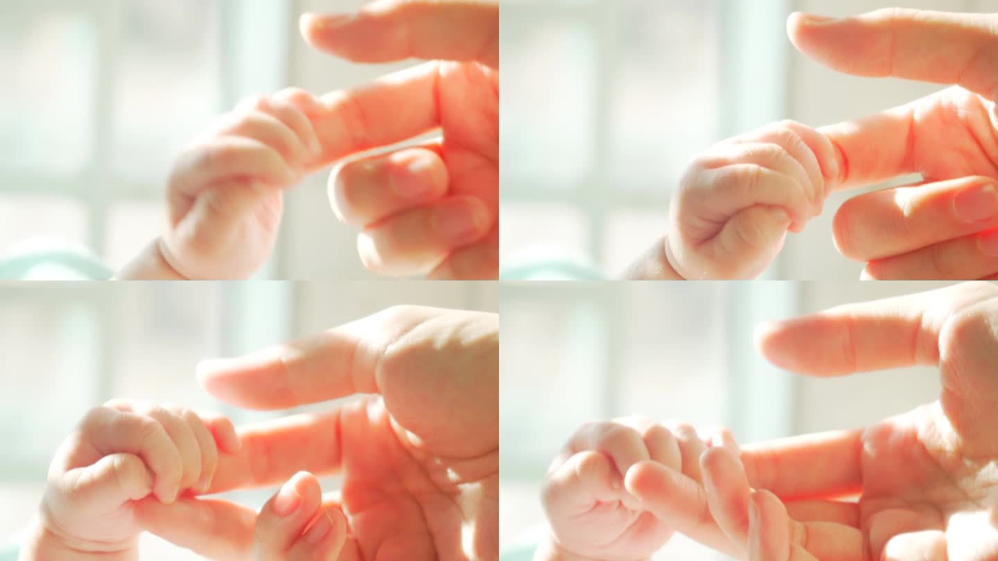 日出时新生儿握着母亲手指的特写