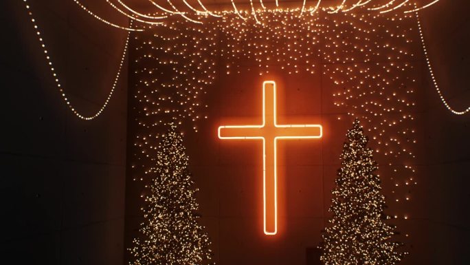 节日照明:教堂内，舒适的霓虹灯从十字架上洒下，在装饰着节日花环的圣诞树上投射出神奇的光芒。