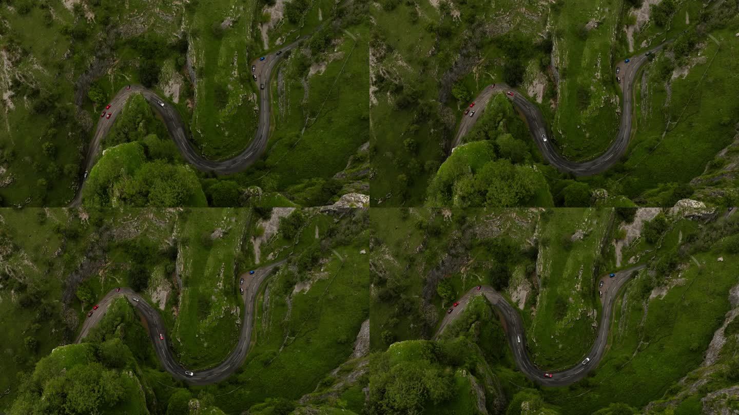 在英国常绿的自然景观中，汽车行驶在蜿蜒的切达峡谷公路上的壮观鸟瞰图