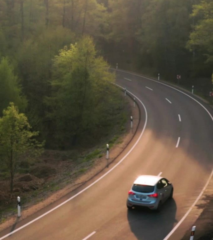 在阳光明媚的夏日，森林公路上的汽车。广角追求拍摄垂直视频卷轴和故事
