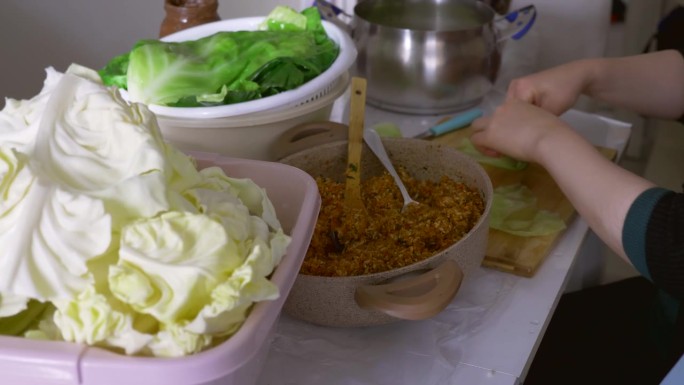 做包心菜的女人小心地把碾碎的混合物放进包心菜里。