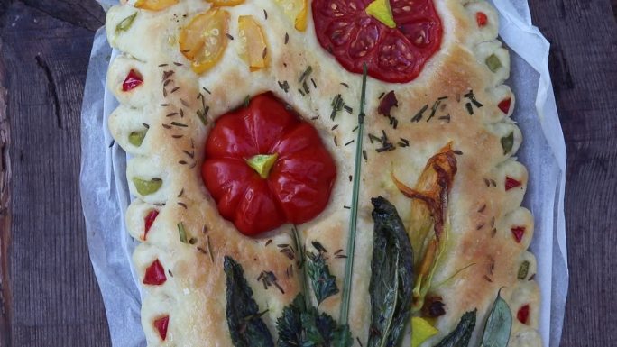 开胃的烤佛卡夏面包配上西红柿和其他蔬菜放在木桌上，还有自制的糕点