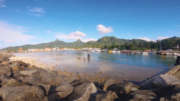 在阿瓦蒂乌港的沙质岩石海湾地区，眺望船只、运输船、建筑物和侏罗纪公园，远处的背景是饱经风雨的蓝天