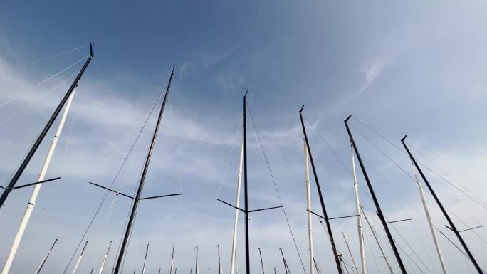 在阳光明媚的日子里，许多桅杆的顶部，停泊的帆船，蓝天的背景