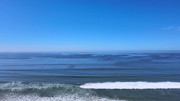 用这个令人惊叹的飞行镜头提升你的感官，捕捉迷人的蓝色海浪无缝过渡到清澈的蓝天。