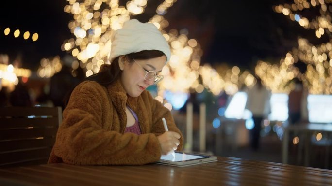 日本一名亚洲孕妇坐在夜市边用平板电脑工作