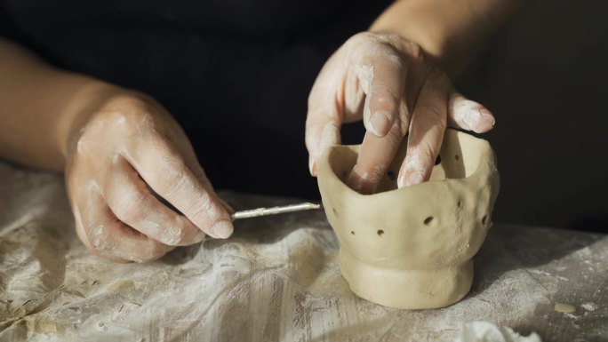 一名妇女用黏土工艺品中的一种工具——烛台打洞。