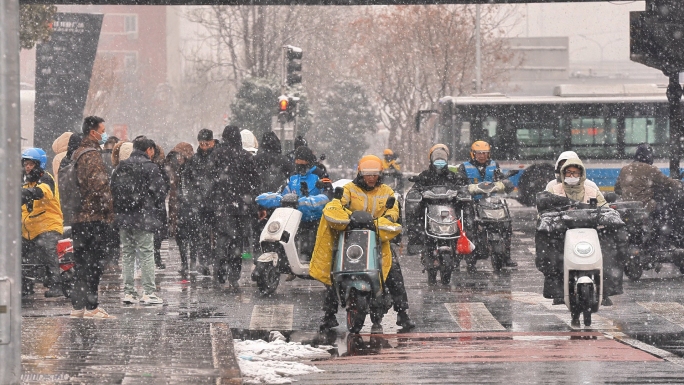 暴雪城市骑行者街道人流外卖快递奔波人群