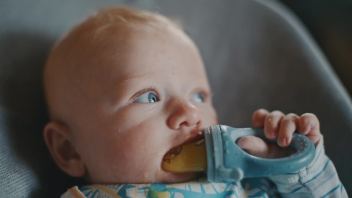 一个可爱的小男孩在家里享受着从奶嘴里拿出来的芒果泥。这个亲密的手持视角捕捉到了小家伙喂食时可爱的混乱