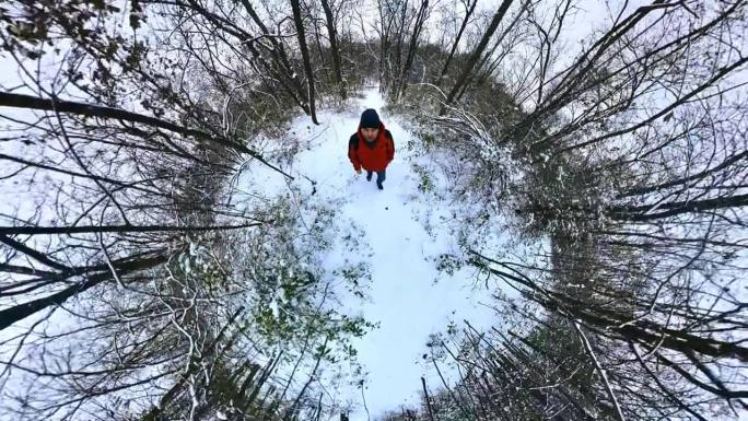 一名身穿红色夹克的男子走过冬天积雪的森林