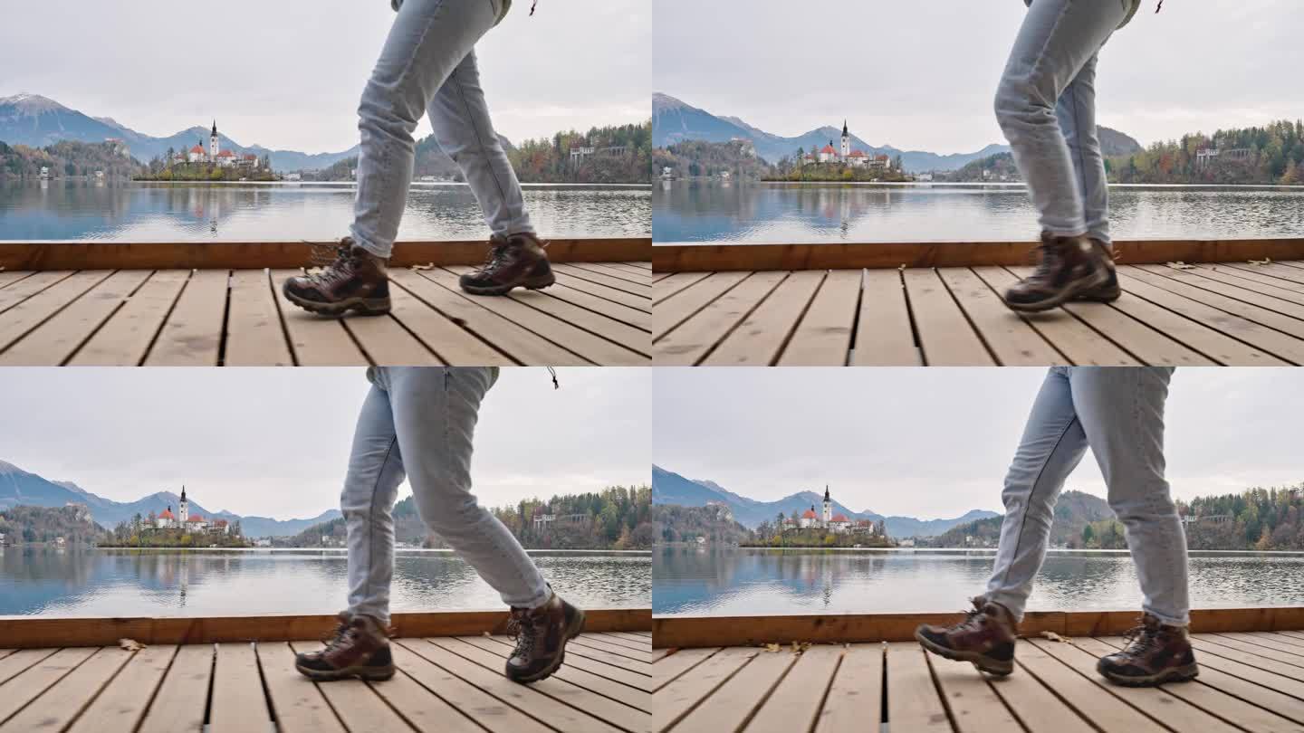 在布莱德湖小岛附近的木板路上行走的穿着登山靴的妇女的低剖面