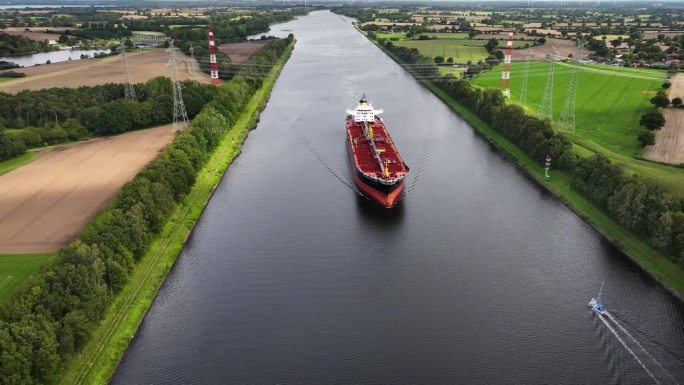 一艘油轮在高压电线下穿越运河的航拍画面。通过基尔运河的工业燃料和石化油轮。