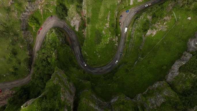电影鸟瞰图汽车行驶在切达峡谷路的蛇形曲线在常绿的自然景观