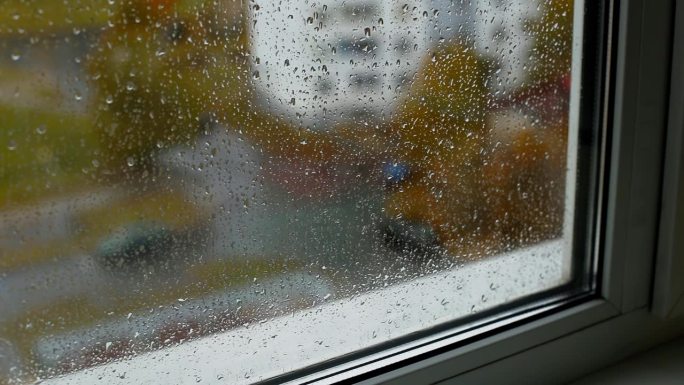 从屋内望向街道，雨滴落在窗台和双层玻璃上。秋天天气寒冷。文本的复制空间，凹陷