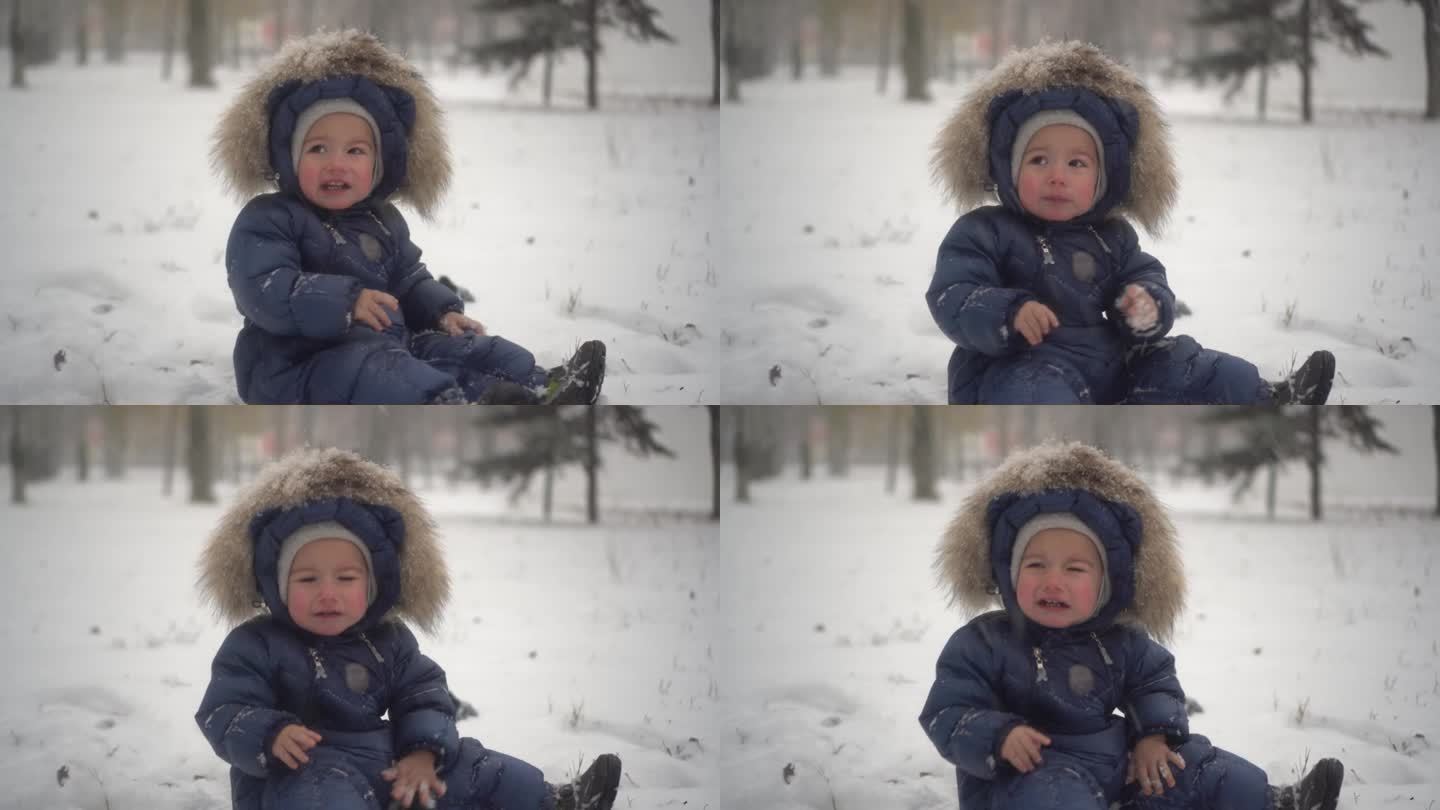 一个小孩坐在公园的雪地里，冷得哭了起来。那个穿羽绒工装裤的男孩双手冰冷。4 k