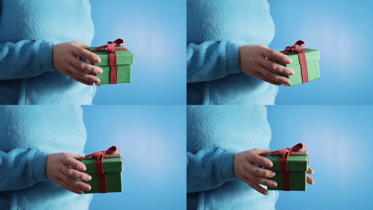 手拿蓝底礼盒，圣诞礼物，彩带包裹，新年惊喜，欢欢喜喜庆祝