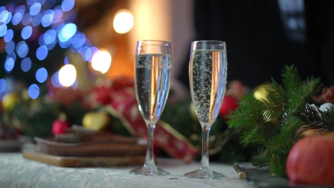 圣诞餐桌上两个香槟酒杯的特写，盛着白起泡酒。