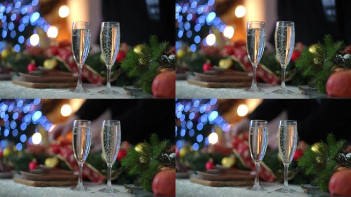 圣诞餐桌上两个香槟酒杯的特写，盛着白起泡酒。
