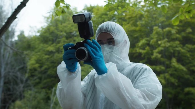 犯罪学家在森林犯罪现场拍照，使用专业相机，从事故中获取证据。调查证据，法医鉴定。侦探，法医