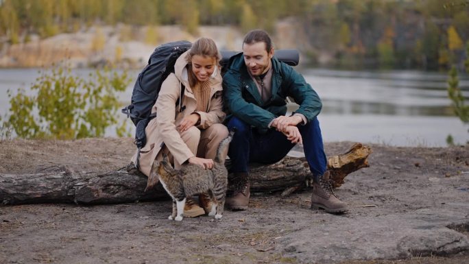徒步旅行的已婚夫妇坐在采石场边爱抚猫