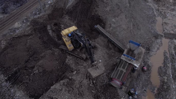 挖掘机用铲斗将泥土运至采石场进行筛分
