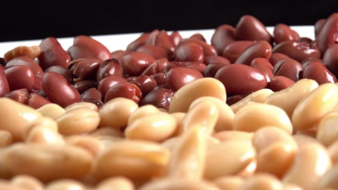 红芸豆罐头和白芸豆罐头在盘子上旋转侧视图。有机蒸豆。墨西哥菜的腌豆