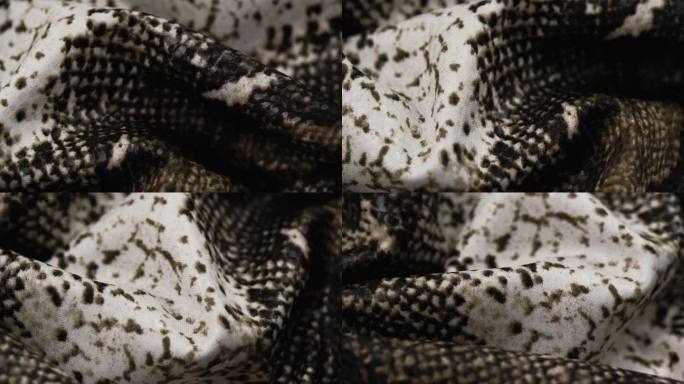 模仿爬行动物皮肤的图案近距离旋转织物褶皱。蛇皮图案。