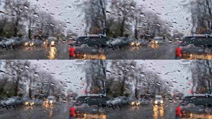 融化的雪和雨滴落在汽车的挡风玻璃上。室外景色模糊，窗外是冬季的雨夹雪