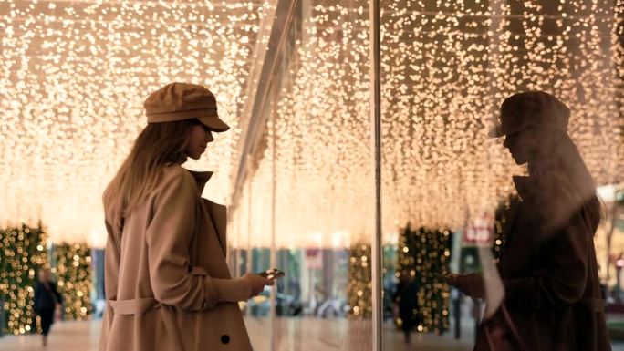 圣诞照片捕捉:女人在冬天的衣服停在橱窗商店