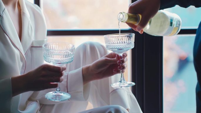 在酒店或家里热恋的情侣。一个男人把香槟酒倒进漂亮的玻璃杯里。约会和关系概念。