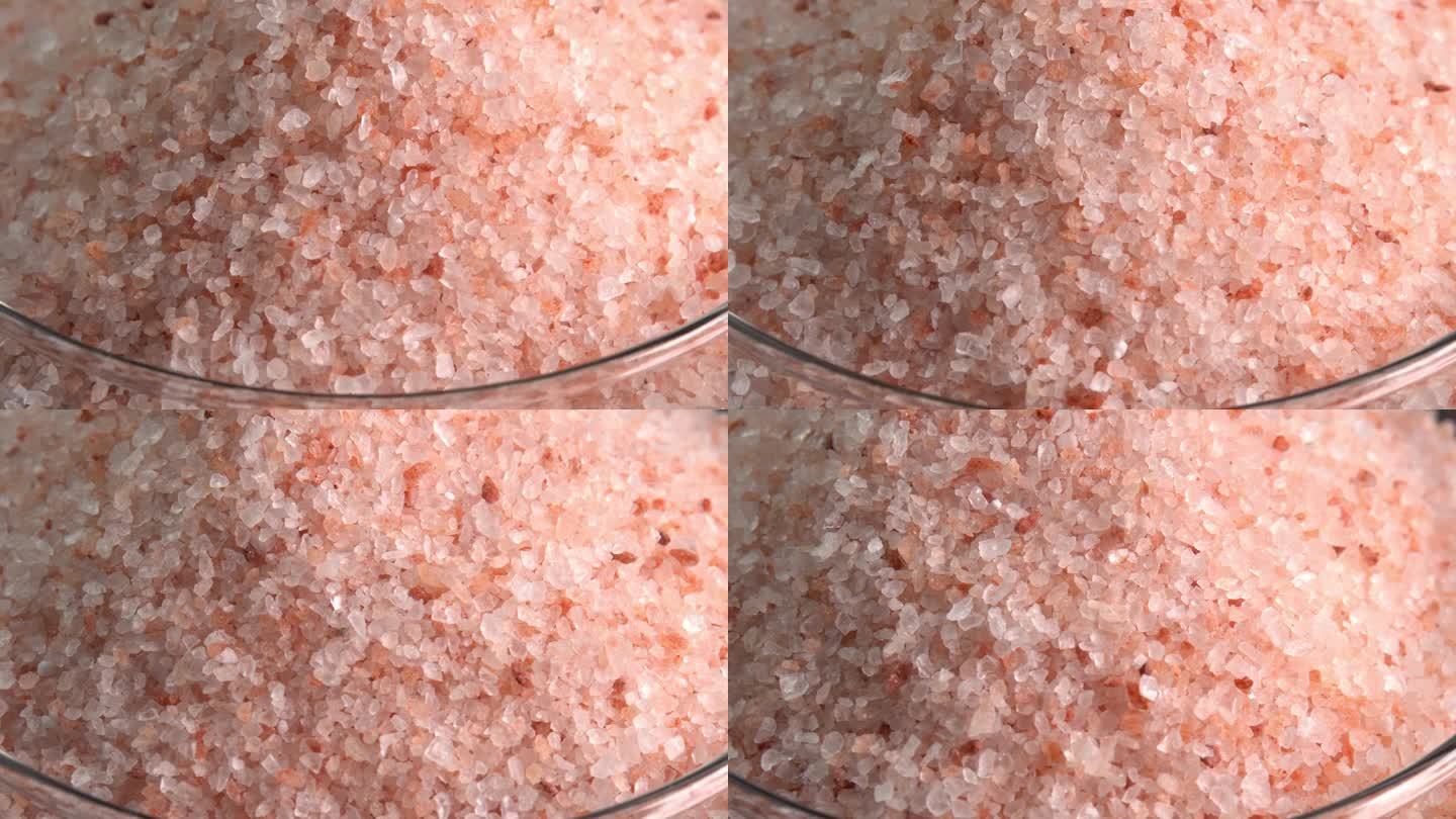 粉红色喜马拉雅盐或岩盐旋转宏观玻璃碗侧光。微量矿物质盐用于烹饪和食物展示，装饰灯和水疗