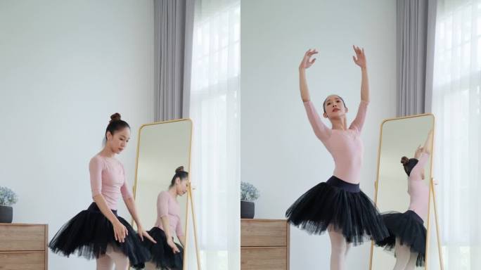 一位美丽的年轻芭蕾舞女演员，身穿粉黑相间的衣服，在芭蕾舞工作室的镜子前练习芭蕾舞。