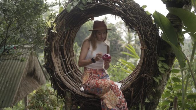 穿着裙子，戴着遮阳帽的女人在丛林里放松，享受着一顿健康的大餐