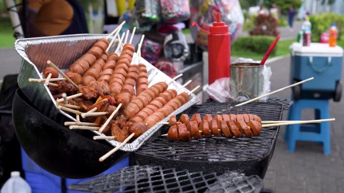 在巴拿马卖街头小吃:挑选烤肉串(香肠和腌肉)，用一瓶瓶的烧烤酱。慢镜头。