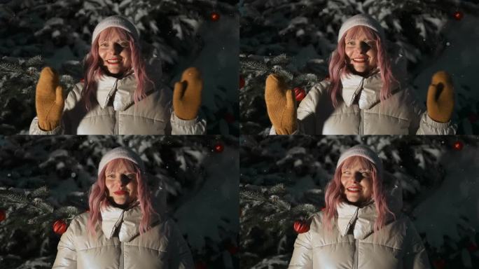 快乐的年轻粉红头发的女人走在冬天的森林里，在冬天的公园里挥舞着手臂