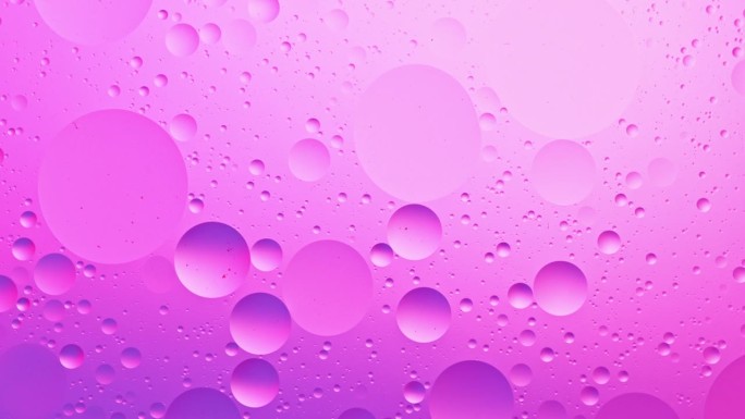 超慢动作流动的粉红色的油泡在水中。