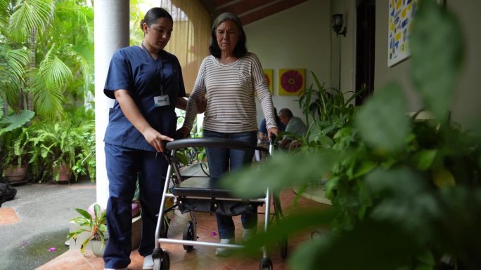 家庭护理人员在养老院帮助老年妇女说话和走路