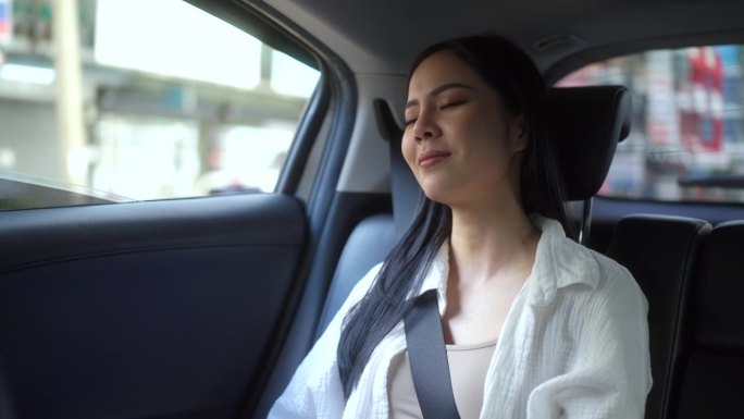 放松的感觉，女人坐在汽车后座系安全带，看着窗外。女开心在车里旅行，在去目的地的路上坐出租车。