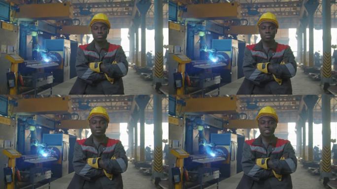 黑人工人在机器人焊接机前摆姿势的肖像