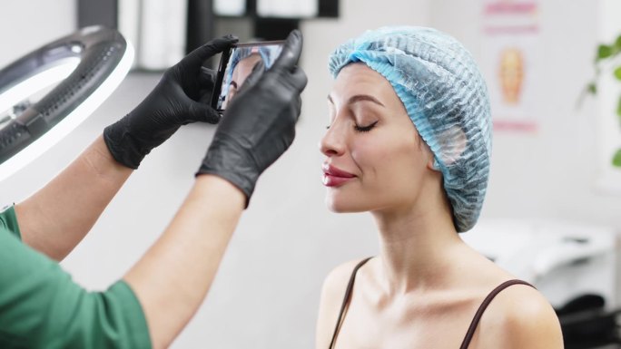 一位美容医生用笔在一位美丽的病人额头上打肉毒杆菌。为一个美丽年轻的女人准备注射的概念。