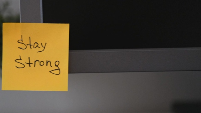 办公室的显示器上贴着一张黄色的纸条，上面写着“保持坚强”。