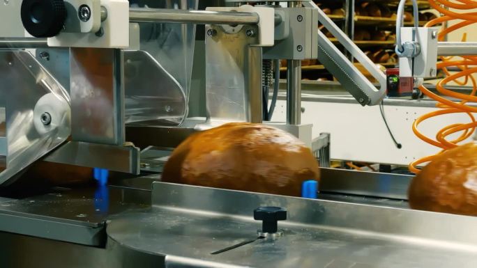 在面包包装生产线上，新鲜面包被包装在透明的包装薄膜中