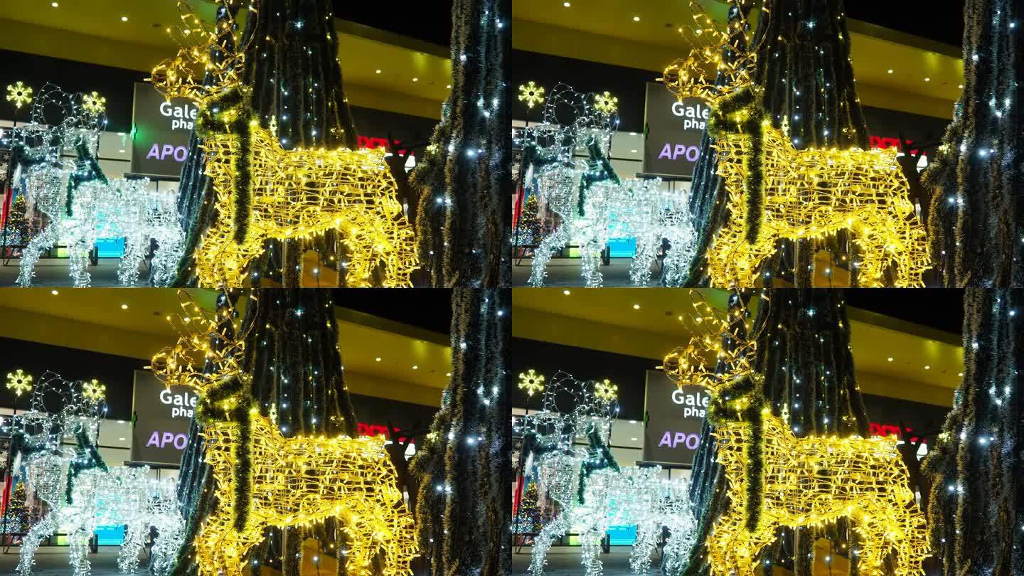 鹿在夜里发光。新年快乐的圣诞装饰用银白色黄色金色燃烧的灯泡。散景闪烁的灯泡花环。寒假。