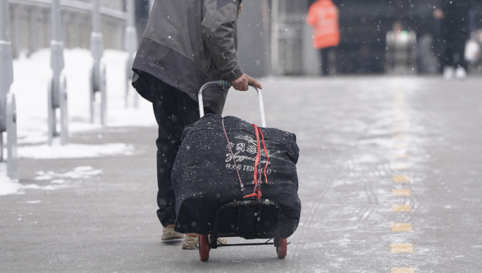 农民工拉着行李在雪中行走
