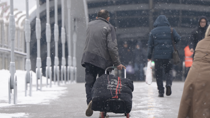 农民工拉着行李在雪中行走