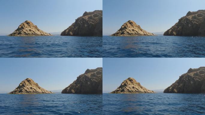夏天，从法国鲁斯岛的一艘观光船上看到的山脉、岩石、海水和帆船。