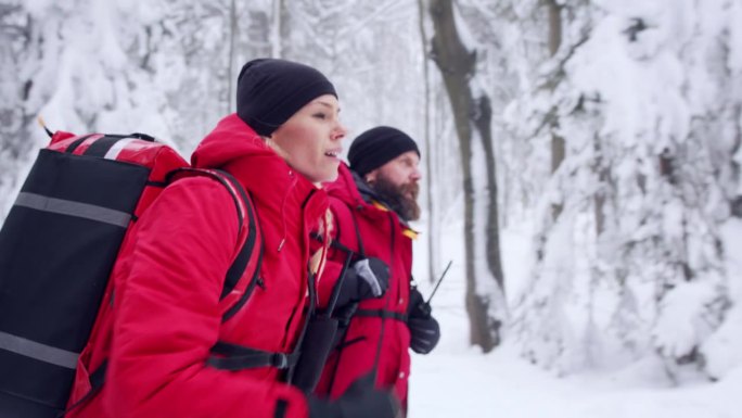 冬季在森林中进行户外登山救援服务的医护人员的侧视图。