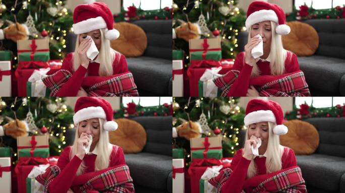 年轻的金发女郎坐在圣诞树旁的地板上在家哭泣