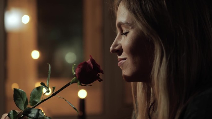 日期，情人节，周年纪念。烛光下浪漫的女子闻着红玫瑰